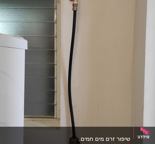 צינור מים עם ברז אדום על קיר לבן